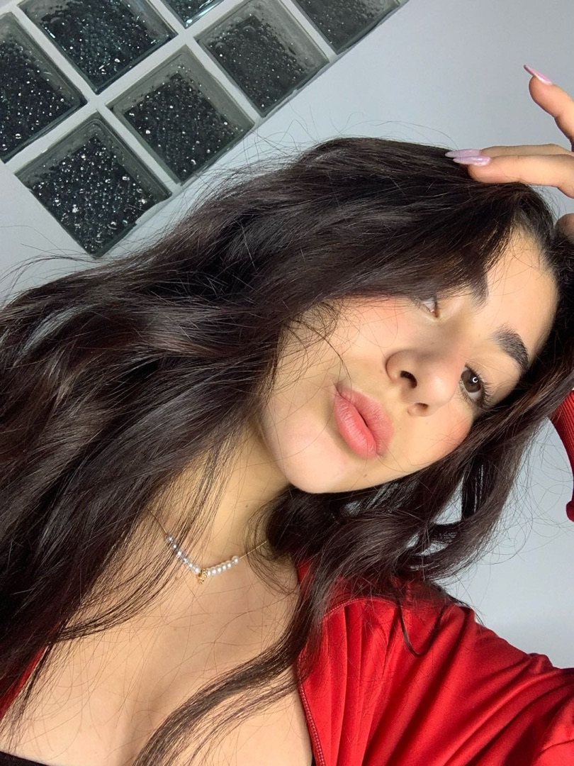 Woman in a red top with wavy dark hair smiling at the camera