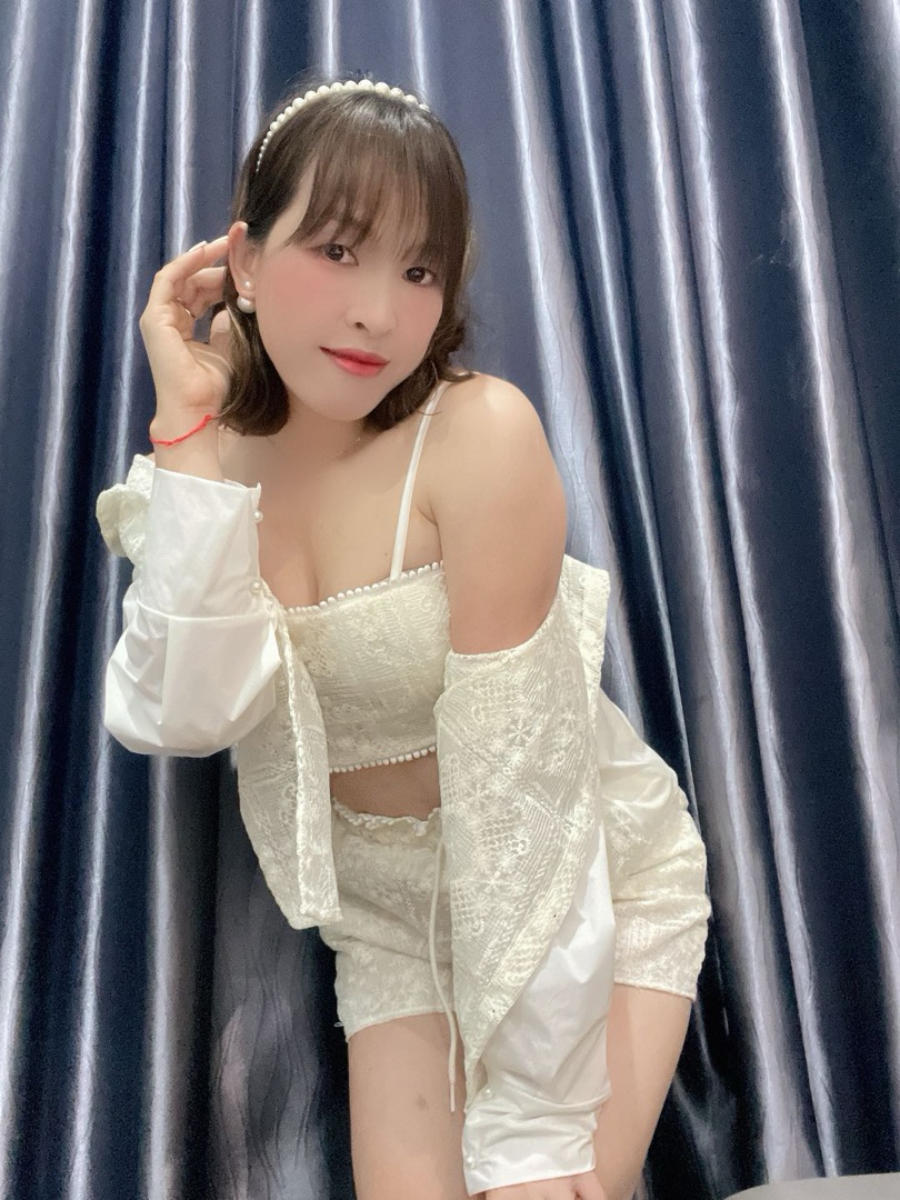 Woman in a white lace outfit with a pearl headband smiling