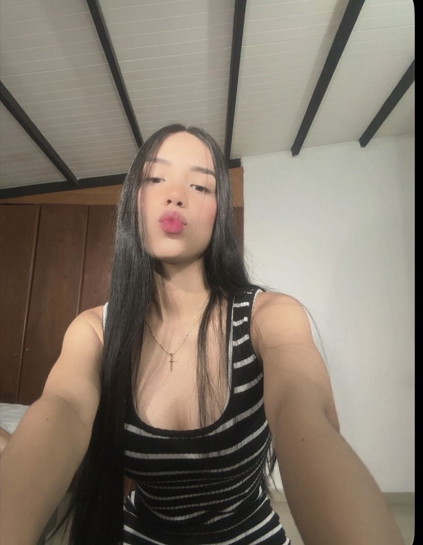 Woman in a striped top chatting on camera from her room