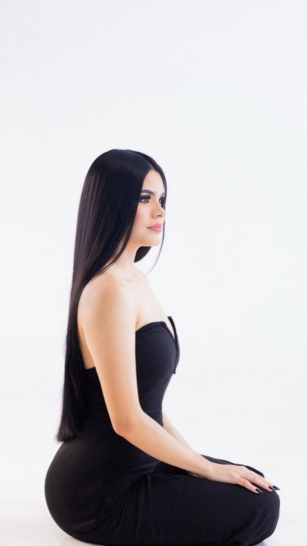 Woman with long black hair in a black dress, editorial studio portrait