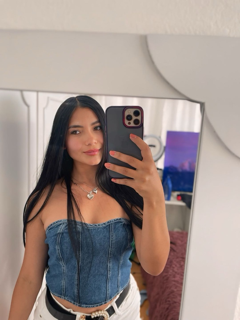 Woman in a denim top taking a mirror selfie at home
